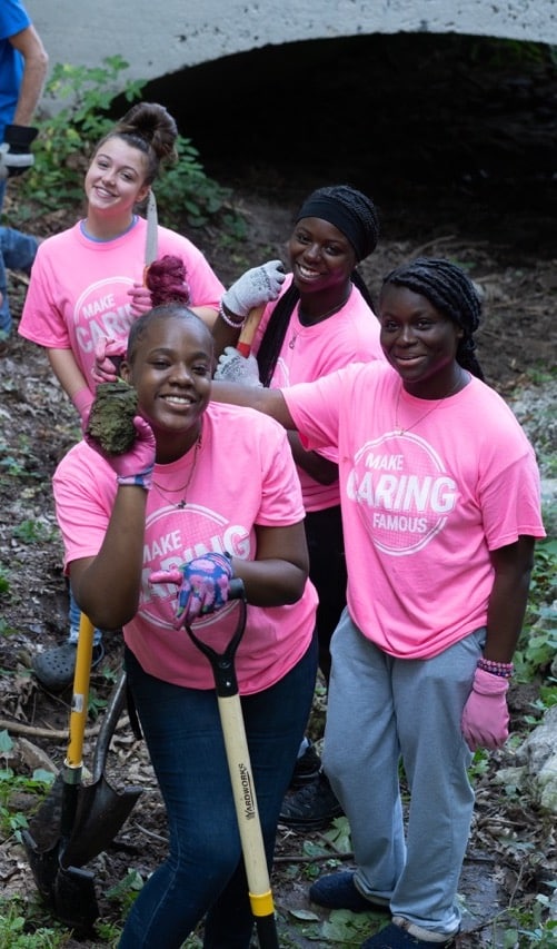 Group of smiling women in pink t-shirts working outside.