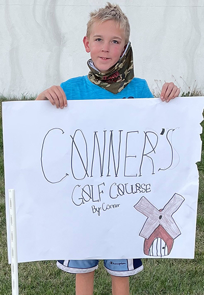 Young boy holding a golf course sign
