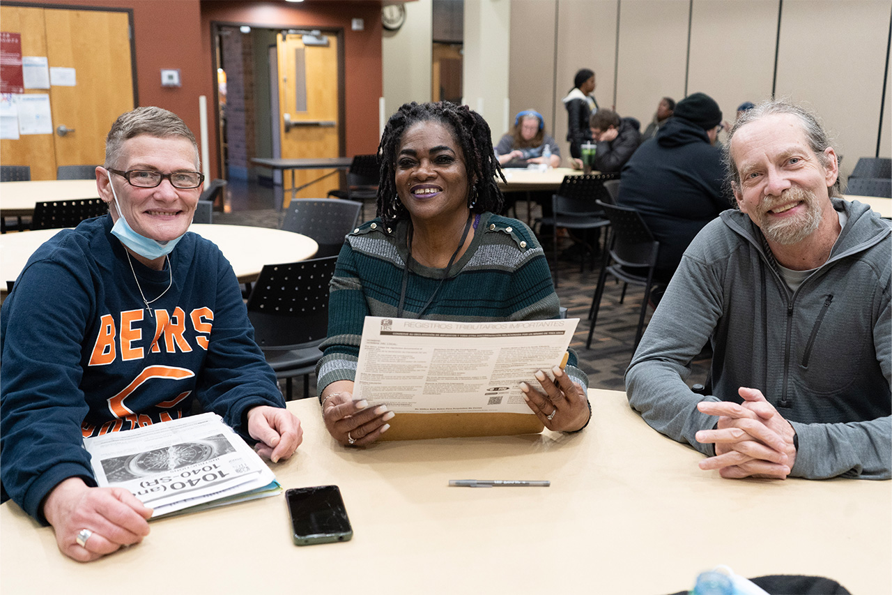 women helping a man and a woman prepare their taxes.