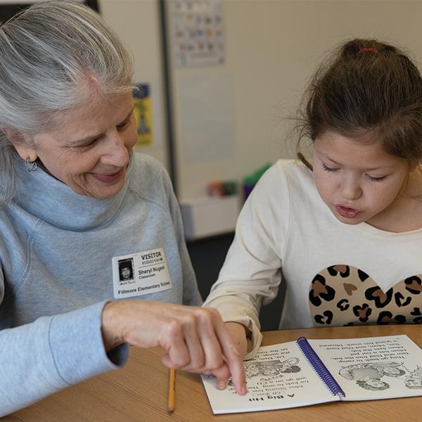 Older-woman-reading-with-an-elementary-school-student