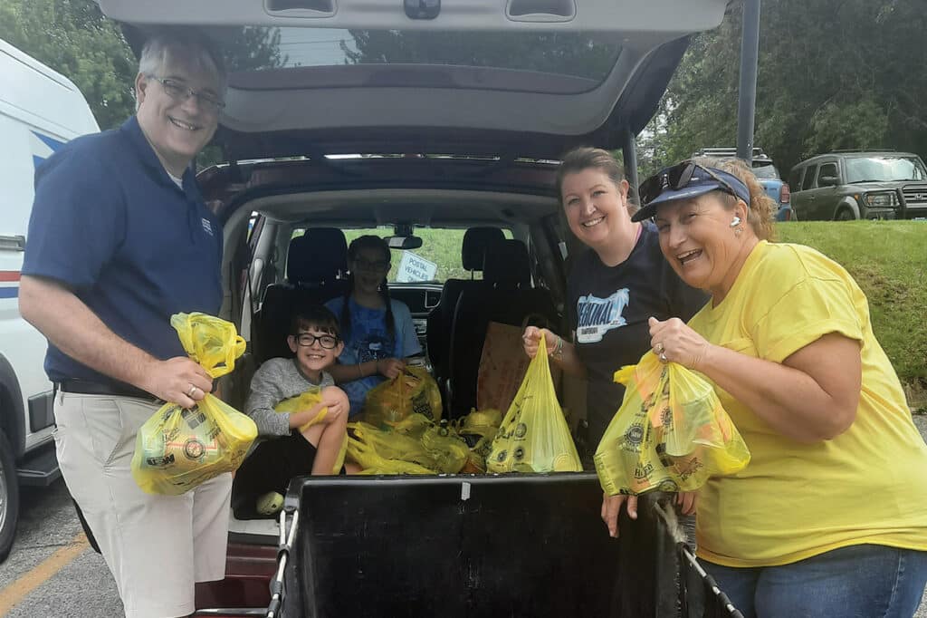 Family-unloading-bags-of-food-from-the-back-of-their-vehicle