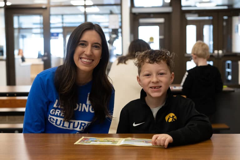 woman reading with an elementary age student in a cafeteria