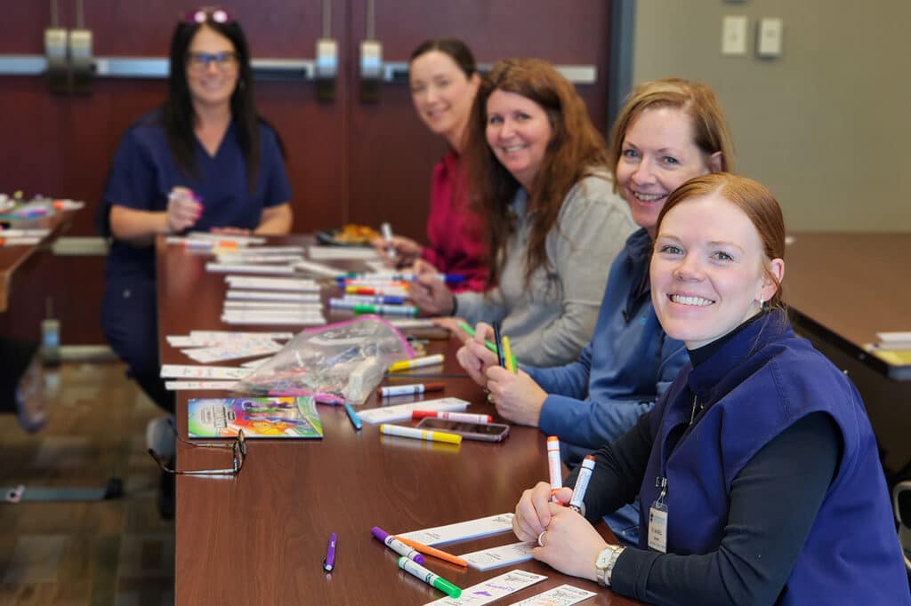 group of women sitting at a table putting together activity kits for students