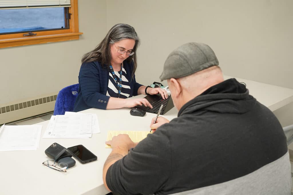 volunteer at a table helping a man prepare his taxes