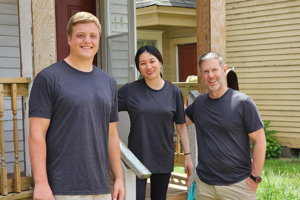 three people standing outside on a front porch