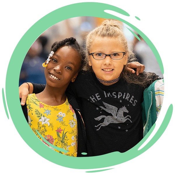 two elementary age kids standing in a hallway with hands around each other
