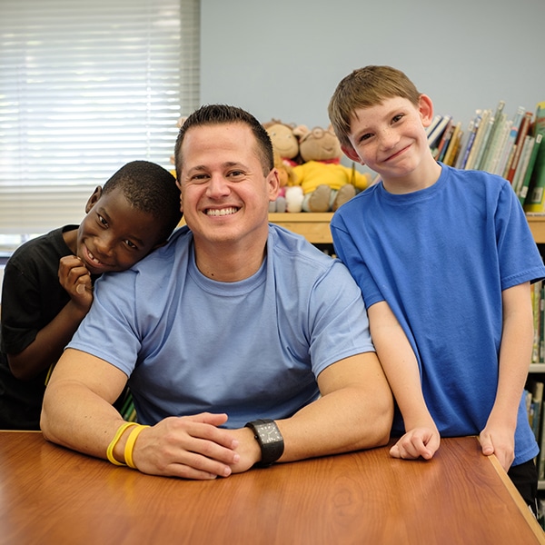volunteer-sitting-with-two-students