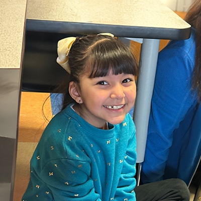 young-girl-sitting-under-a-desk-smiling