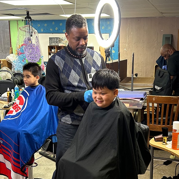 man giving an elementary student a haircut