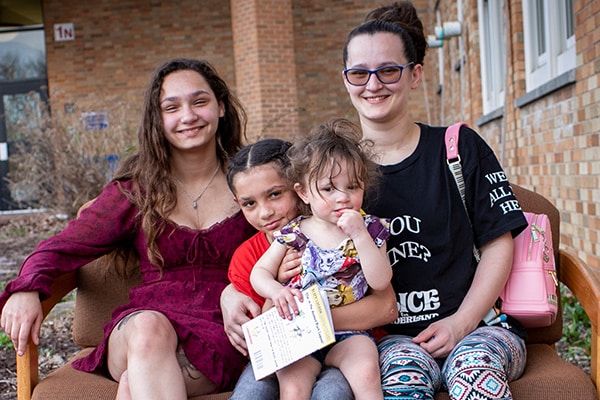 mother and three kids sitting outside on a couch