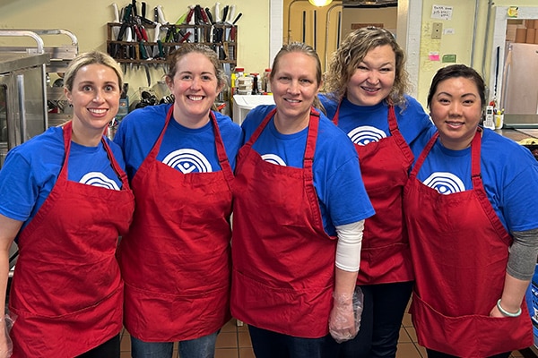 group of five women wearing aprons in a kitchen