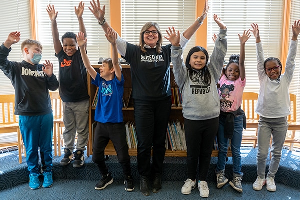 woman with a group of kids with their hands in the air