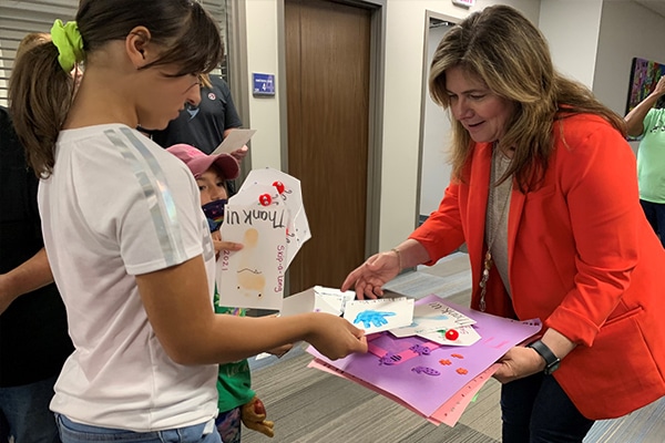 woman in red blazer receiving thank you cards from a student