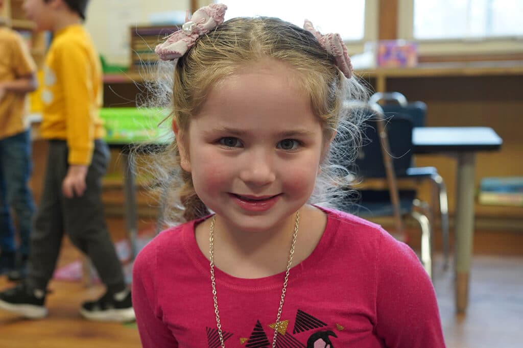 young girl in pink shirt with pink bows in her hair