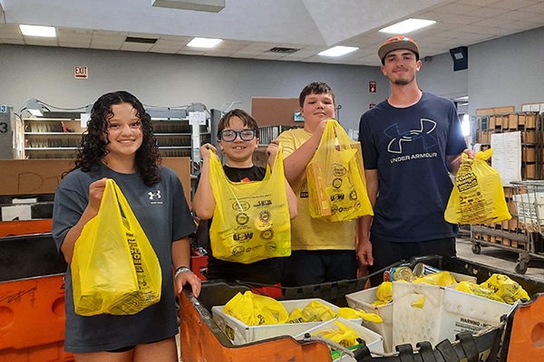 group of food drive volunteers holding yellow bags of food