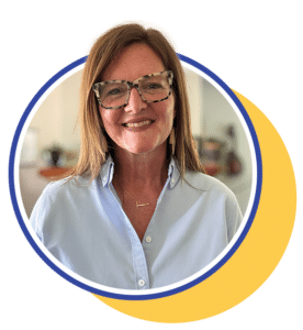 woman in a light blue button up shirt and glasses smiling for a picture