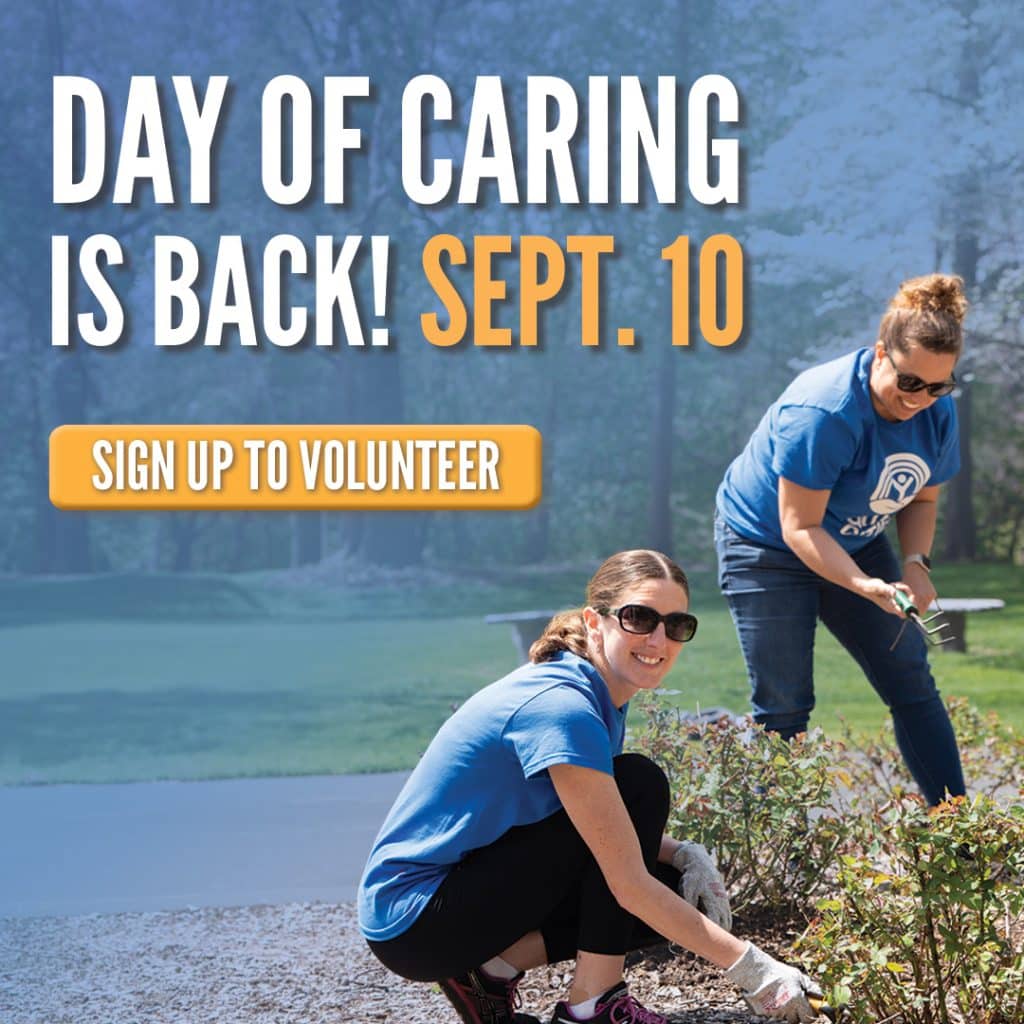 two women in blue shirts trimming some bushes outside
