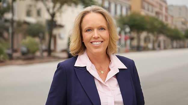 women in a blue blazer and white shirt smiling for a picture outside