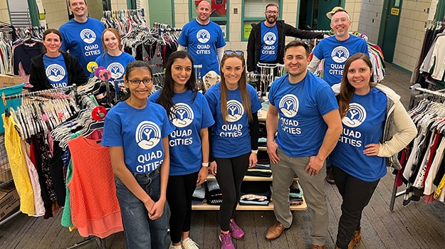group of volunteers in blue shirts surrounding by clothing racks