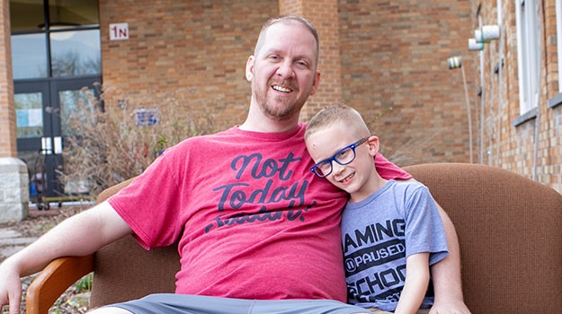 father and son sitting outside with arms around each other