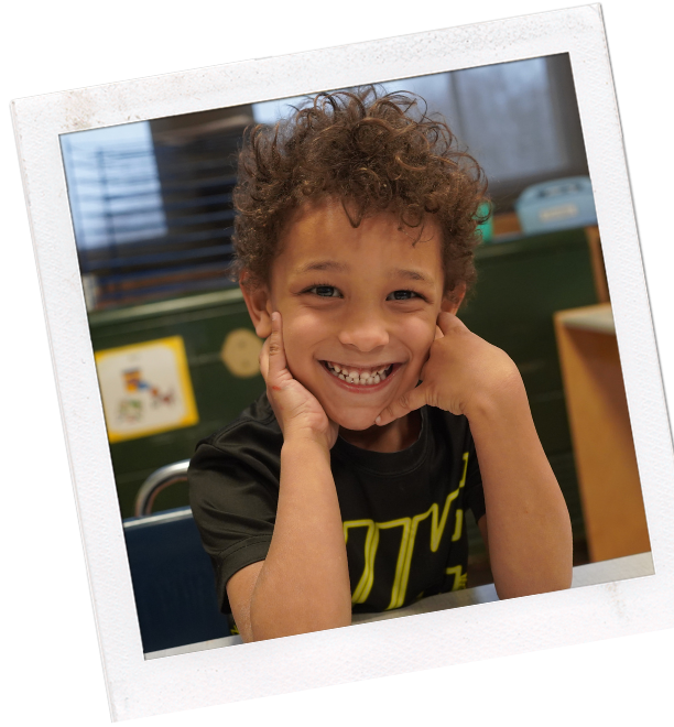 young boy with hands up by his face smiling