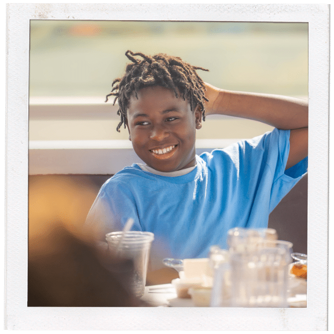 boy in a blue shirt with one arm behind is head smiling