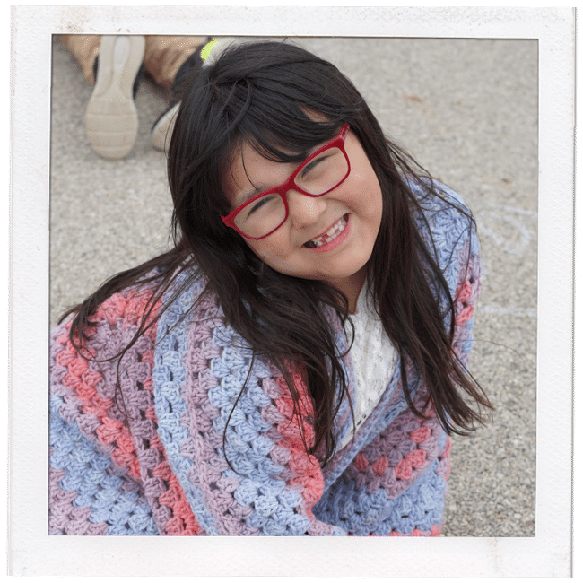 young girl in glasses and pastel colored shirt smiling