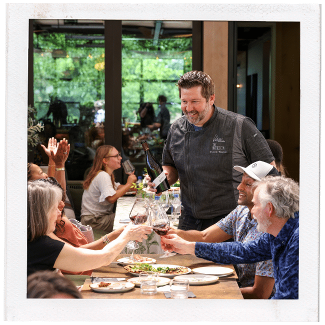 chef pouring wine at a table of guests at a restaurant