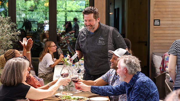 chef pouring wine at a table of guests at a restaurant